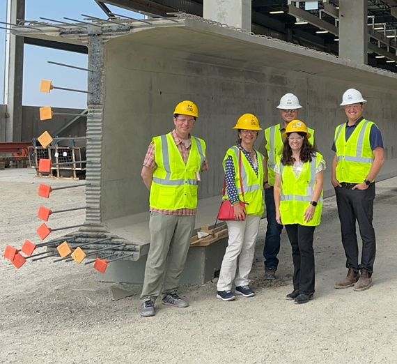 Melina leans against a wall wearing a green shirt